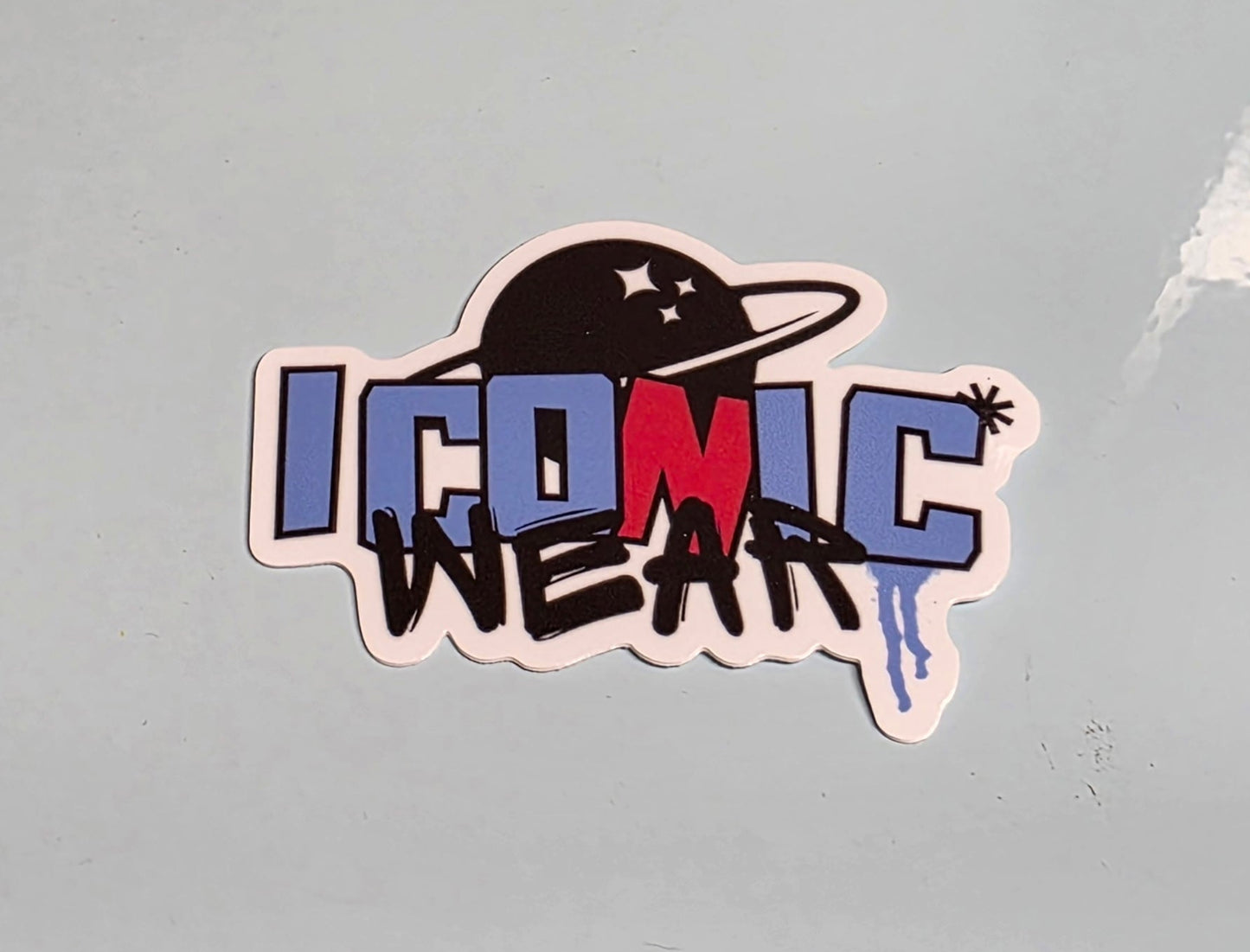 Sticker with 'Iconic Wear' text on a textured surface