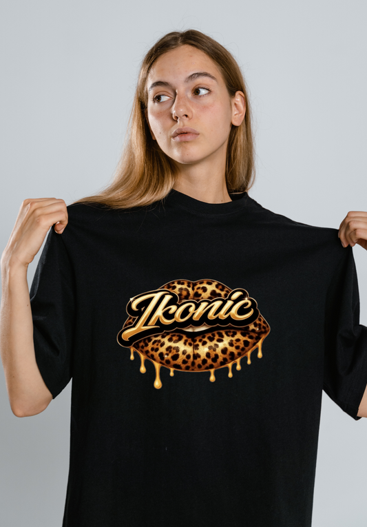 Person holding a black t-shirt with 'Ikonic' logo featuring leopard print design on a plain background